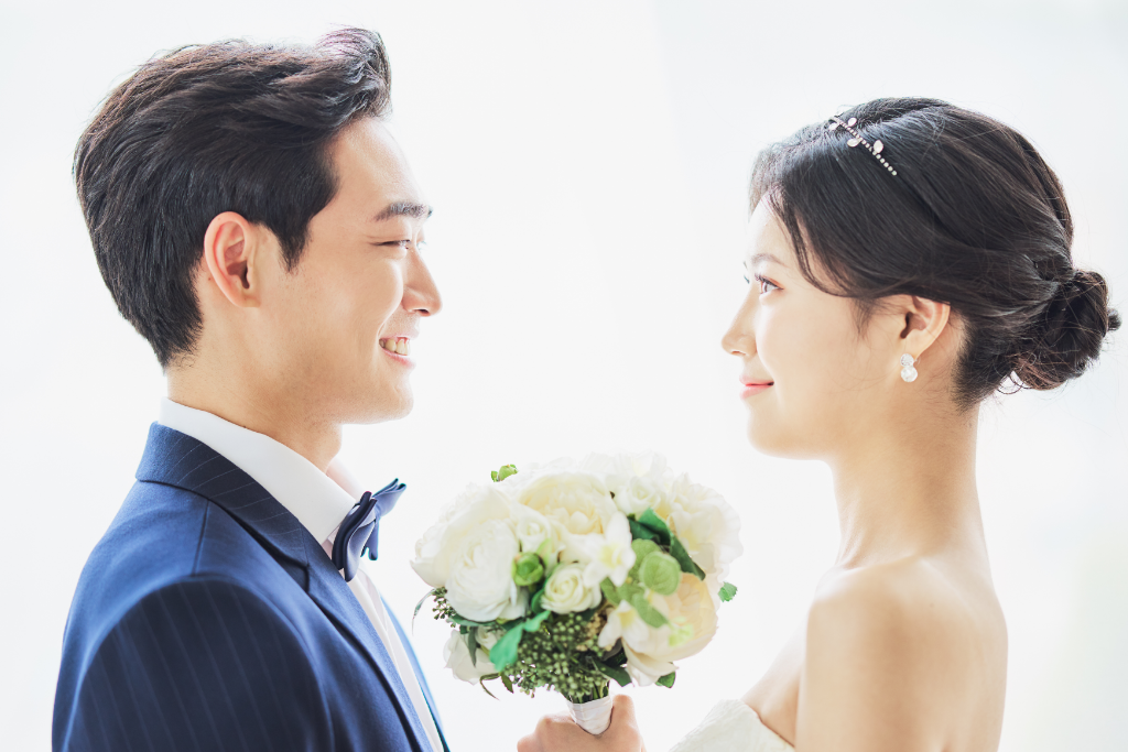 タキシード姿の男性とウェディングドレスを着た女性が向き合い、笑顔を交わしている結婚式の様子